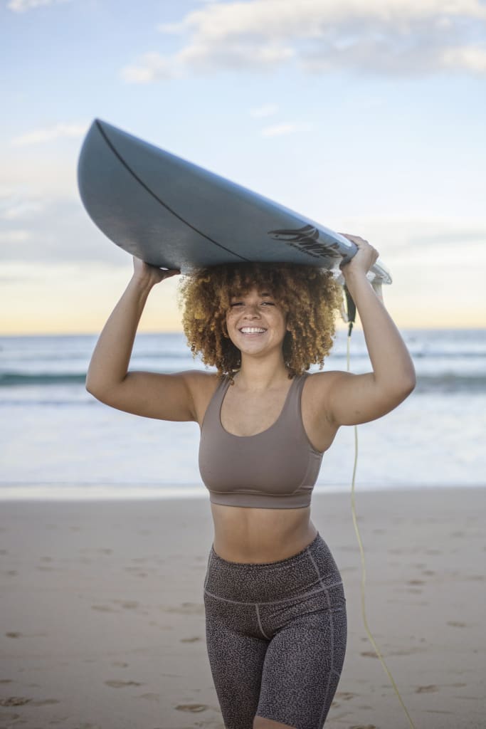 Mixed race woman balancing surfboard on head